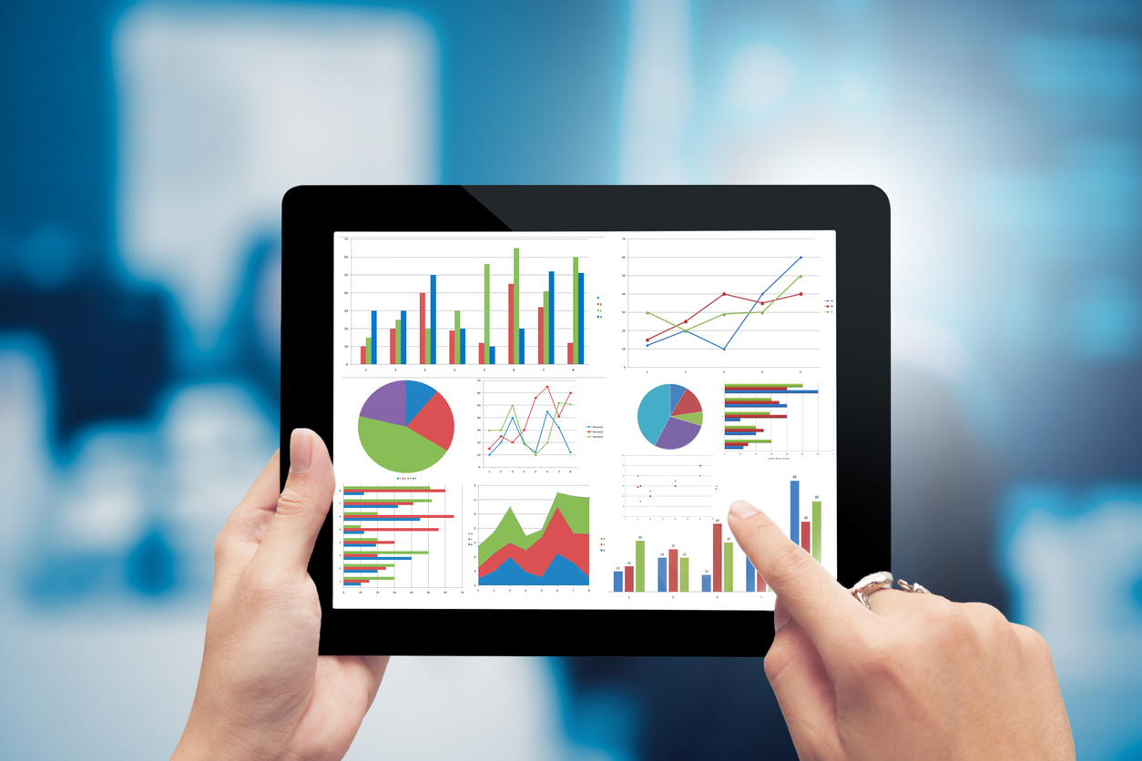 Hands holding tablet with various charts onscreen