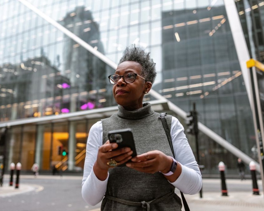 Older woman in a city uses cellphone to navigate