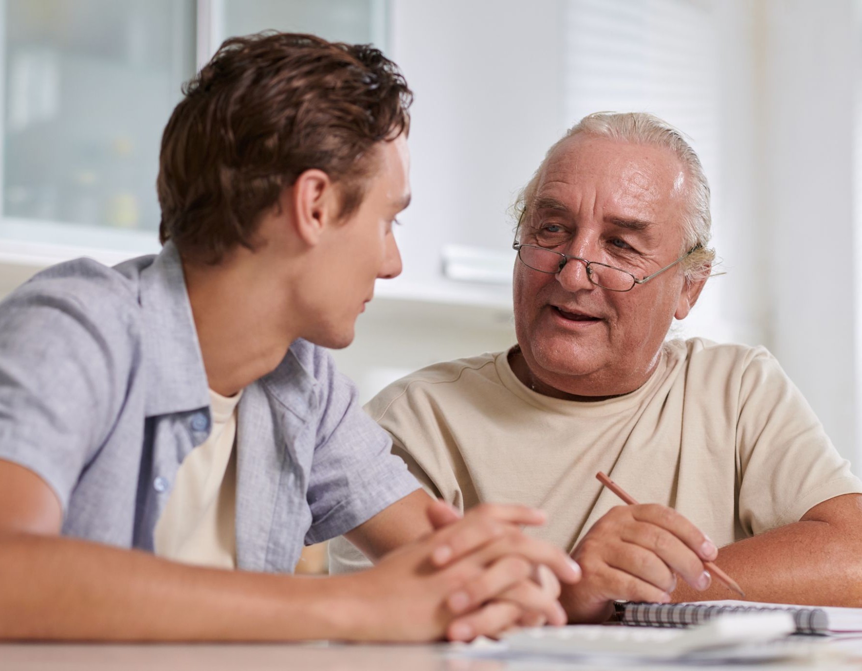 older man and young man sitting at a table talking
