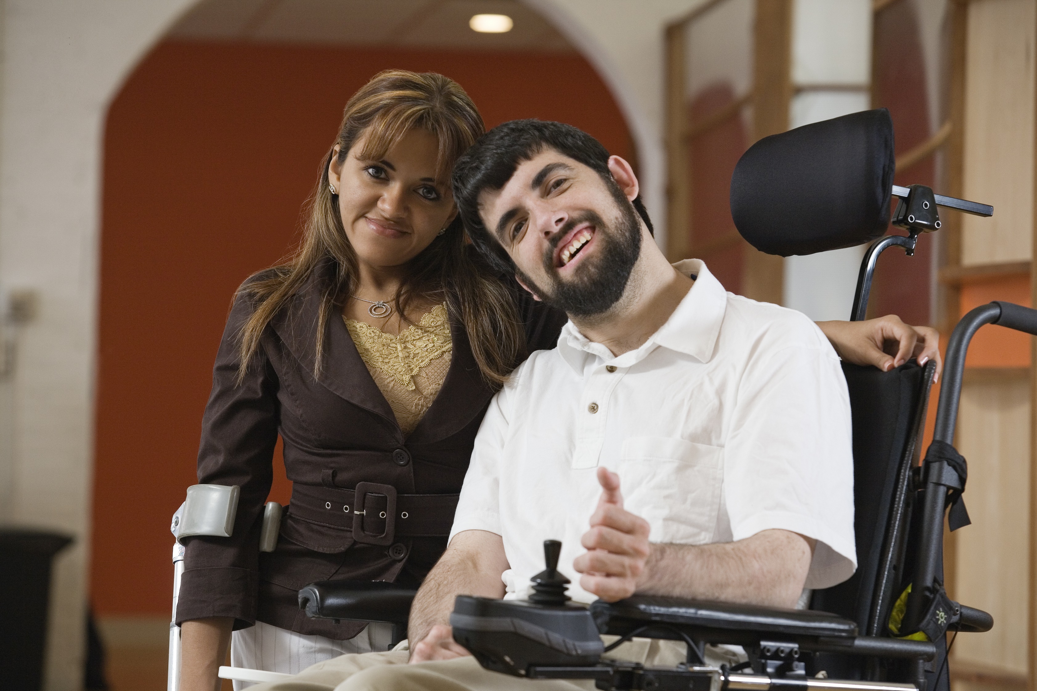 Woman using crutches standing next to man using wheelchair
