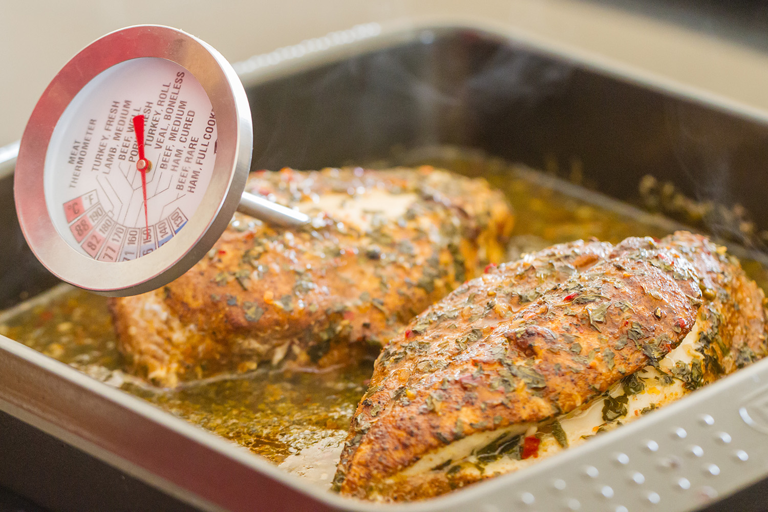 a thermometer checking the temp on a chicken breast