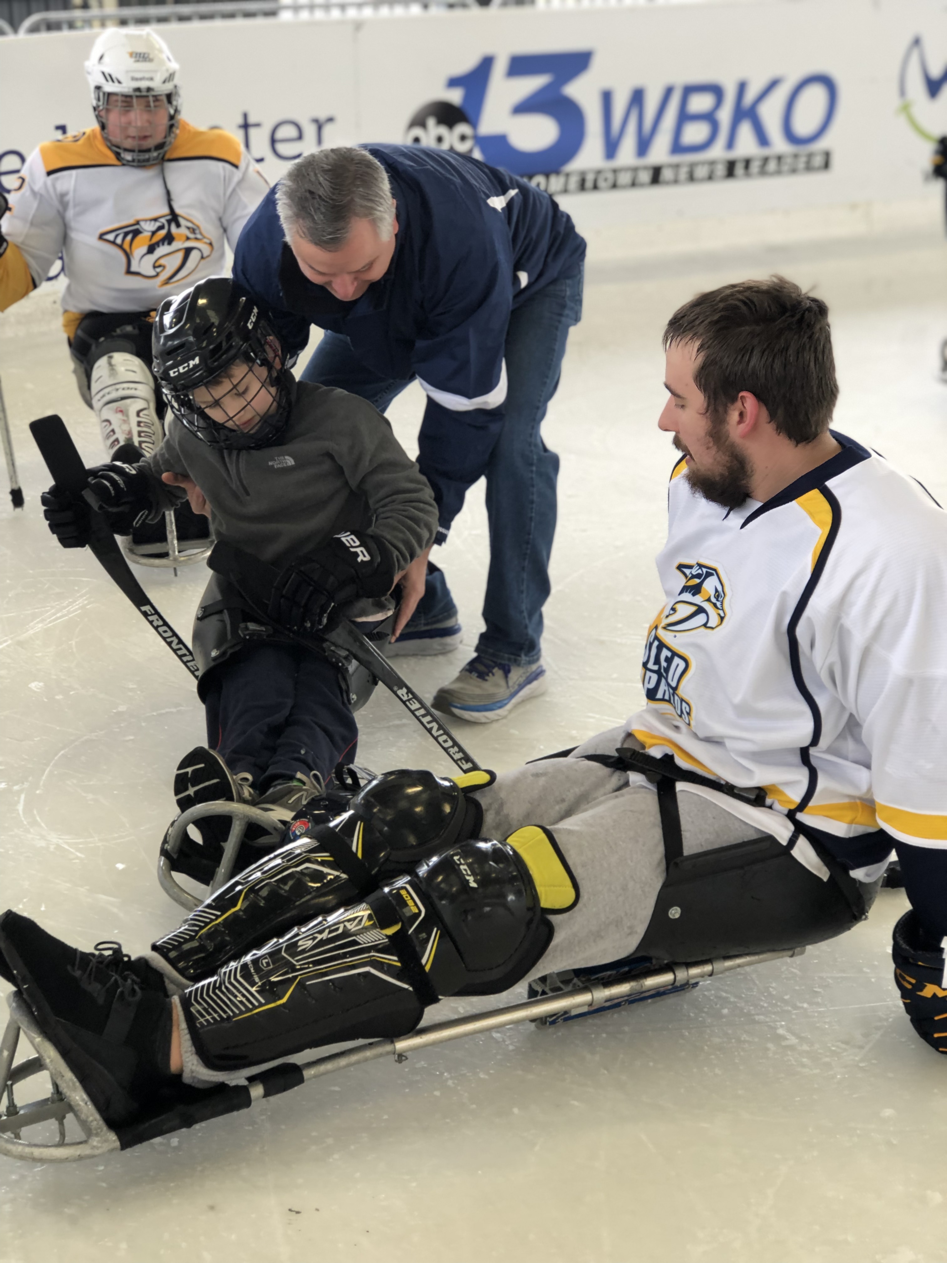 Man demonstrates sled hockey to boy