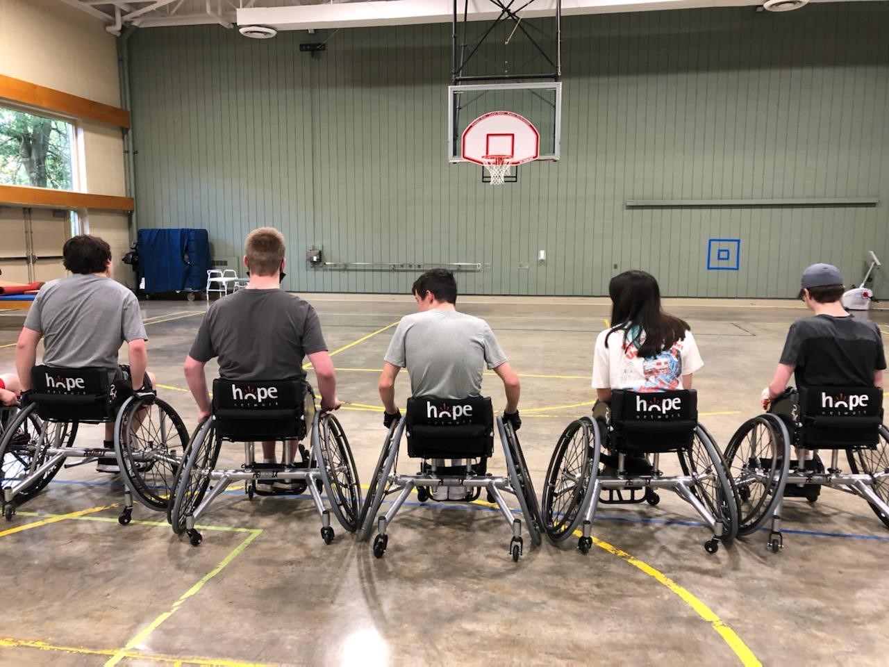 Participants sitting in basketball wheelchairs on the court