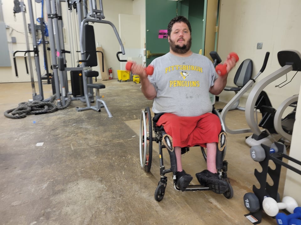 A man using a wheelchair exercises by lifting weights