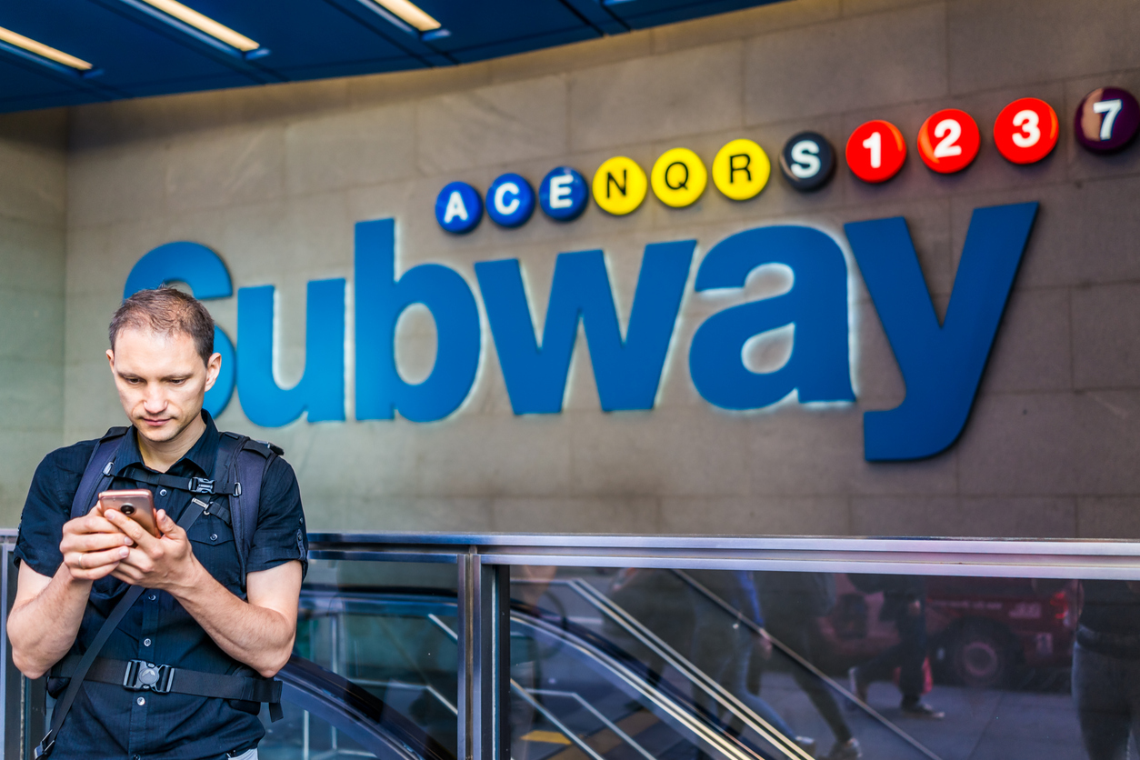 Man uses his cellphone outside of a subway station
